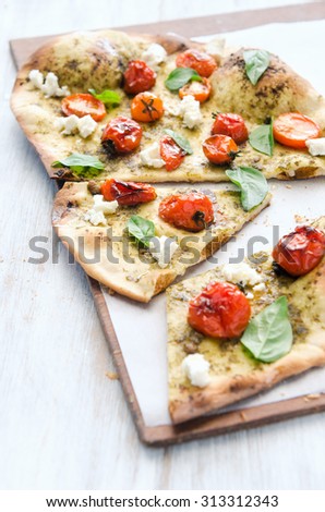 Slices of gourmet thin crust pizza with roasted tomato, fresh basil and feta cheese