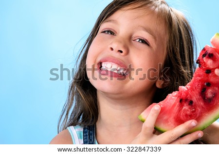 Cute smiling young girl with fresh juicy watermelon summer fruit, healthy living and diet concept on blue background