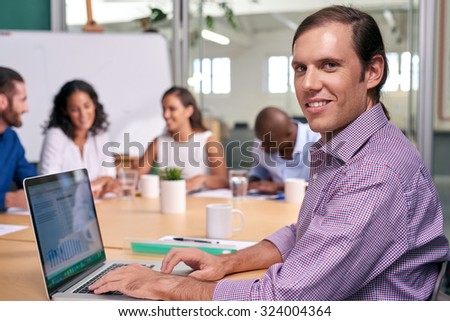 portrait of professional business man during coworkers boardroom meeting with laptop computer taking notes