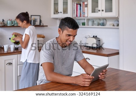 couple relaxing with coffee tablet computer in home kitchen