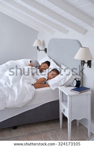 peaceful young couple sleeping comfortably in bed at home