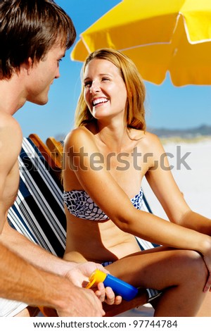 Summer beach couple take care of their skin with sunblock lotion of high SPF for maximum protection