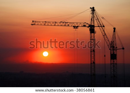 Hoisting cranes and construction site on sunset.
