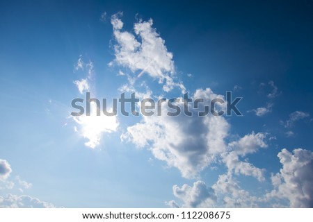 Bright sun and blue sky with fluffy clouds