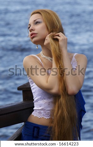 Beautiful young girl with long red hair and pearl ear-ring on the bank of Neva river  (Saint Petersburg)