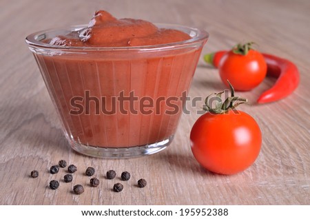Tomato sauce in a glass gravy boat on a wooden surface