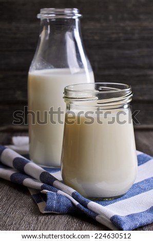 yogurt and milk in a glass container on striped cloth