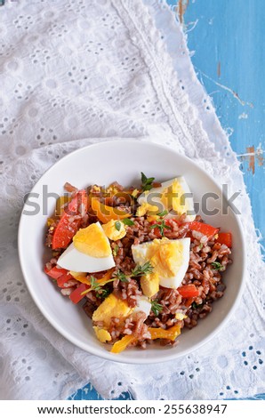 Salad of red rice, paprika and eggs with thyme leaves