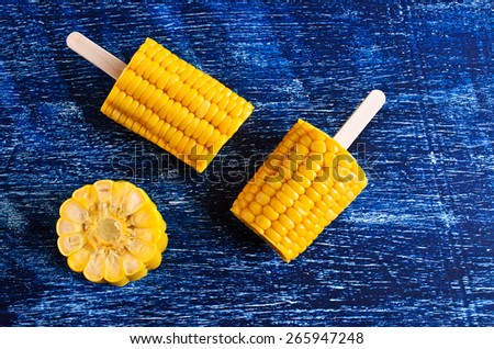 Cut corn on the cob on a stick on the blue surface