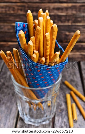 Bread sticks, long and thin, in a paper envelope lying on a wooden surface.