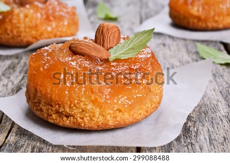Cake with jam, decorated with almonds and mint, on a wooden surface