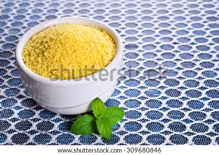 Couscous in a ceramic dish on a transparent cloth. Selective focus.