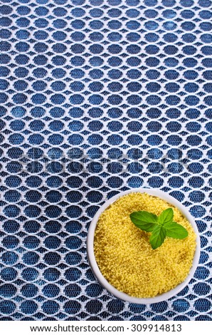 Couscous in a ceramic dish on a transparent cloth. Selective focus.