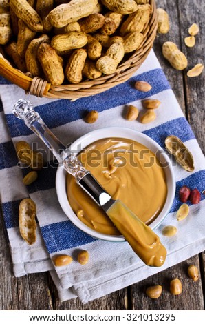 Peanut butter on the tip of the knife on the background of ceramic ware. Selective focus.