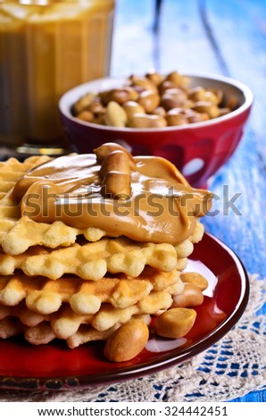 Waffles with peanut butter in a ceramic bowl on a wooden surface. Selective focus.