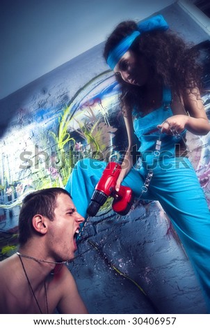 Beautiful girl and attractive boy  working at a graffiti wall. Girl using a drill press, and tyrannize the boy