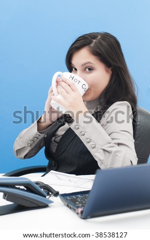 Portrait of businesswoman drinking coffee at the office with laptop and phone on the desk