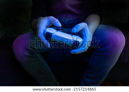 Similar – Image, Stock Photo Man playing video game at home. Gamer playing online in dark room lit by neon lights. Competition and having fun