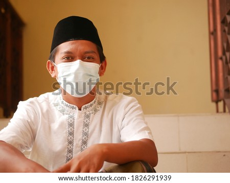 Potrait of Indonesian young man with face mask in mosque. Asian man with wearing cloth face masks for eid mubarak / Ied Fitr. Indonesian moslem with face mask during pandemi. Imagine de stoc © 