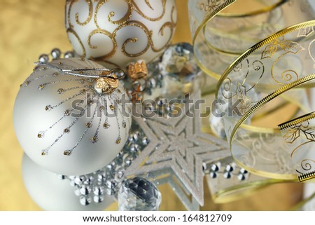Two Christmas baubles, cristal sphere, star and ribbon on golden background with reflections