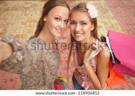 Two  girls - shopaholics  are taking pictures of themselves. High angle view. Shoot looks like its taken from their camera