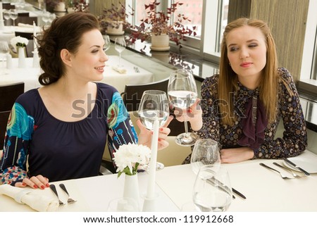 Two young woman are drinking while waiting their order in the restaurant