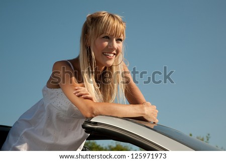 Sensual young woman is standing in the  sport car