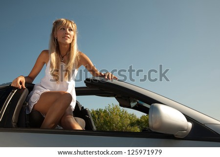 Sensual young woman is standing in the  sport car