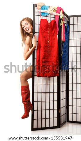 Young woman is Looking out of the folding screen,a lot of different clothes is is hanging on it