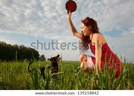 Young woman is playing with her dog with Frisbee