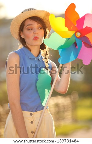 Young happy funny (vintage) dressed woman close-up ,making funny face and holding  colorful weather vane,looking like flower  Picture ideal for illustating woman magazines.