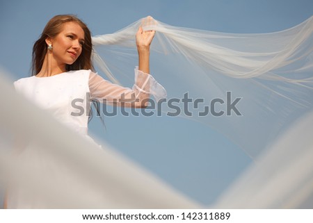 Young cheerful bride is holding her flying veil.Selective focus