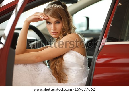 Young sensual bride sits in the red car.Selective focus.  Professional hair and make -up