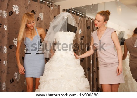 A Bride-To-Be shopping  with her girlfriend for a wedding dress in a Bridal Boutique.