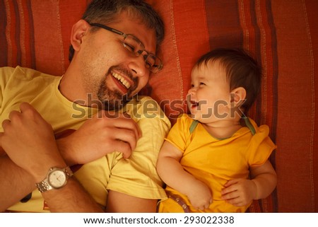 Happy baby and father laughing. Lying on the bad,shooted from high angle.