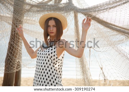 Young fashion model in straw hat  with the seine outdoors. Professional styling,hairs, make-up.