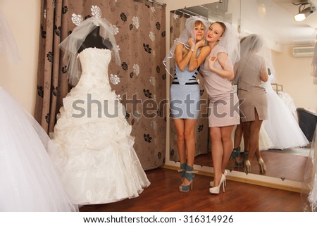 Two girlfriends - A Bride-To-Be and bridesmaid - having fun -Trying On A Wedding veils