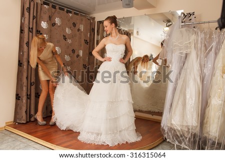 Two girlfriends - A Bride-To-Be and bridesmaid Trying On A Wedding dress