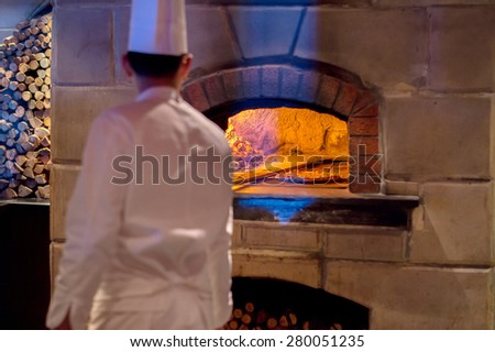 Master Chef baked pizza by the fire burn in brick traditional vintage oven