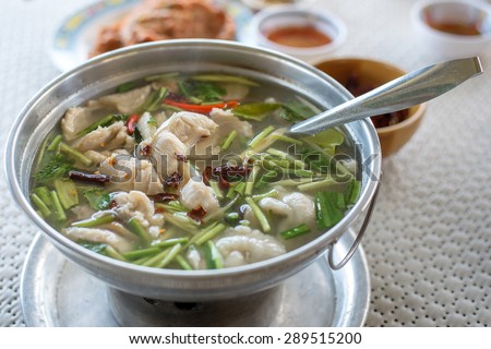Thai clear spicy hot & sour soup (Tomyum) with boiled asian red tail cat fish fillet and herb usually served in a metal pot heated by a charcoal fire