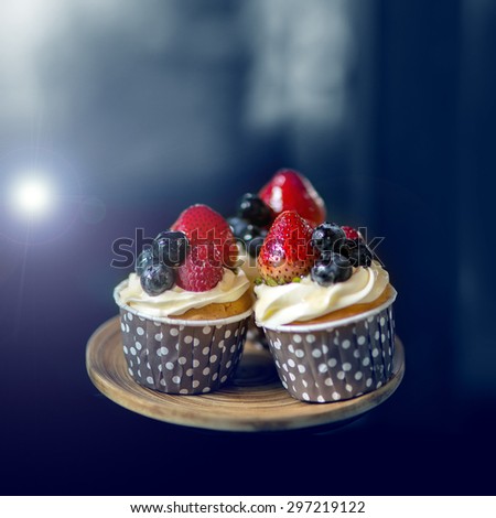 Mix of fruit berries topping on cup cake represent Strawberry , raspberries , mulberries and blueberries decorate on wooden tray