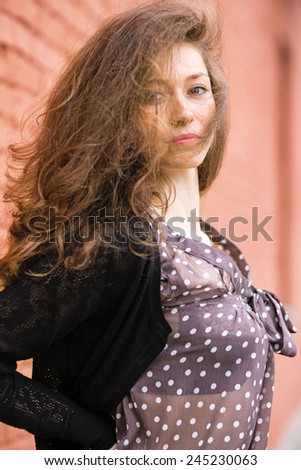 Beautiful young woman near brick wall.