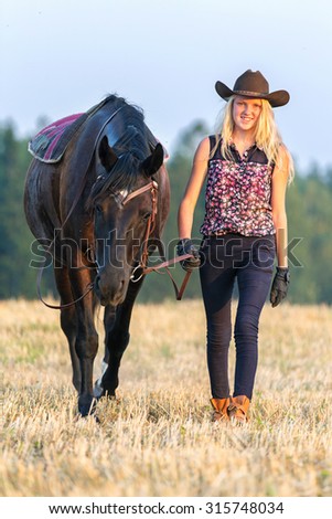Teenage girl leading black horse.