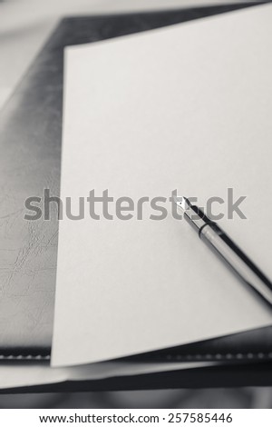 Blank sheet of paper with pen on wooden background