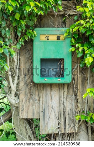 A Green Mailbox with Wooden Plates Installed on The Banyan Tree , The Two Chinese Letter Stands for \