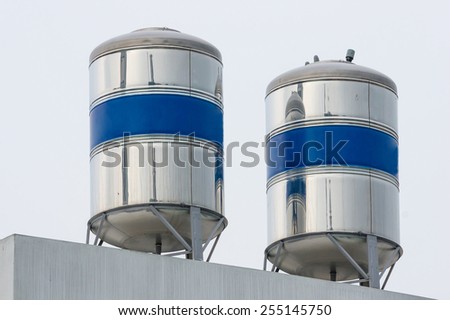 Two Water Tanks Made of Stainless Steel on Top of The Roof. The Middle Section of The Tanks Are Painted in Blue Color.