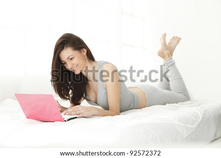 young girl smiling at her computer while reading or chatting ol-line