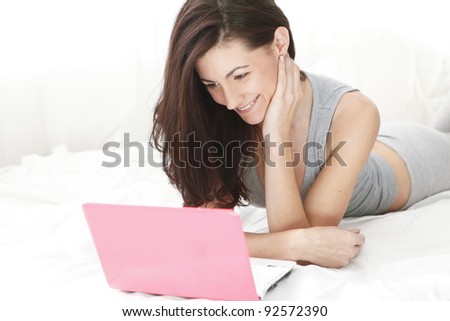 young girl smiling at her computer while watching media
