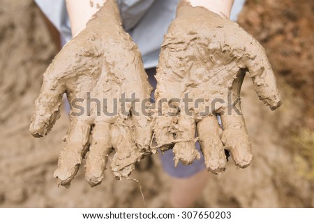 Mud clay on woman hands standing in puddle of mud