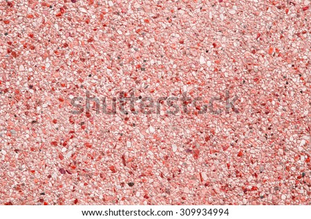 Abstract background of exposed aggregate concrete texture red color